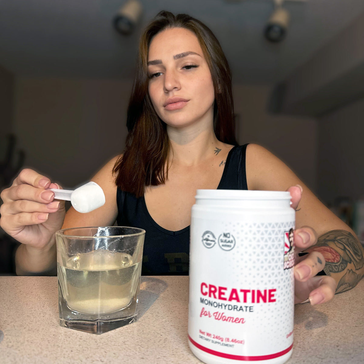 Woman adding creatine scoop to water
